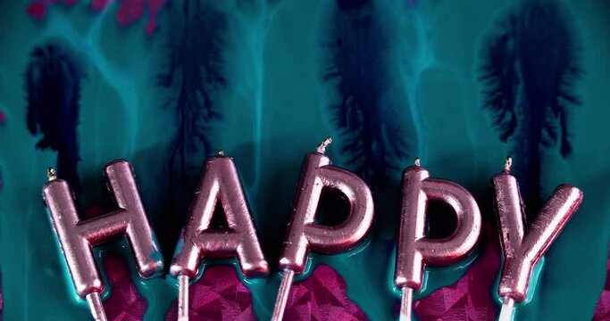 Birthday candles. Happy holidays. Paint drip. Metallic shiny wax letter in iridescent glow light with blue color ink fluid spill flow on pink surface abstract art background.