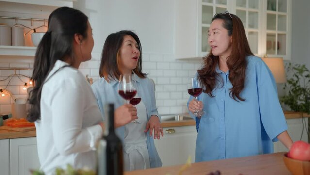 good old friend visit home asian mature woman friend talking standing in kitchen positive conversation good relation friendship reunion home visit casual relax hand hold wine glass goodvibe at home