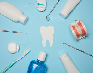 Mouthwash, toothpaste tube, dental floss and medical mirror on a blue background, oral hygiene. Top...