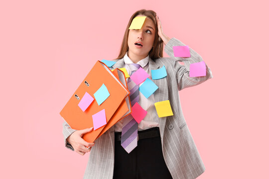 Naklejki Funny shocked young businesswoman with sticky notes and folders on pink background