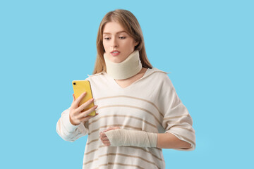 Injured young woman after accident with mobile phone on blue background