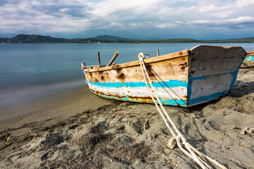 Fototapeta na wymiar Dramatic seascape image of a old weathered fishing boat on the Caribbean coast in Dominican Republic with long exposure.