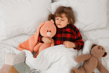 Adorable little girl with plush toys sleeping in bed