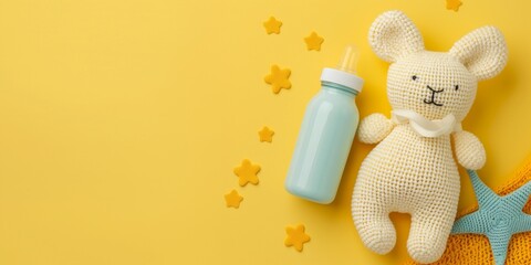 Cute baby product banner, knitted toy and baby bottle laying on tender yellow background with copy space.