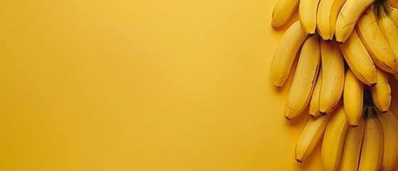   Bananas atop yellow counter with peel on yellow backdrop