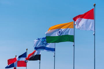 Flags against the blue sky. National flags of various countries flying in the wind. Flags of world states. - obrazy, fototapety, plakaty