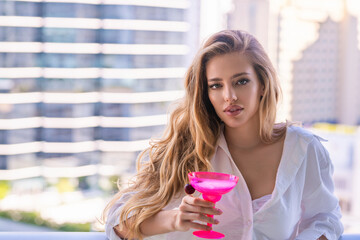 Fototapeta premium Sensual woman enjoy drink coctail at terrace balcony on summer vacation time. Elegant woman drinking alcoholic cocktail on home. Beautiful girl drinking cocktail.
