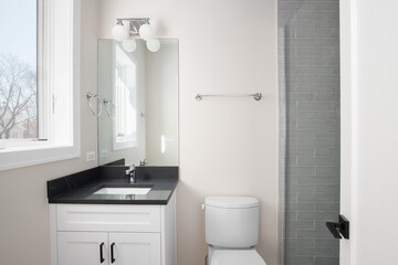 A bathroom with a white cabinet, black marble countertop, and a shower with grey subway tiles.