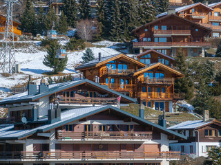 Fototapeta na wymiar Aerial panoramic view of the Verbier ski resort town in Switzerland. Classic wooden chalet houses standing in front of the mountains. 