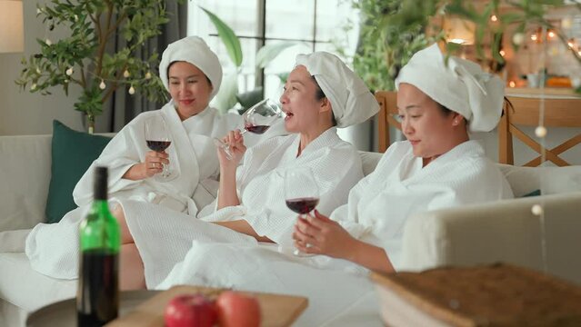 friendship fun and casual relax asian woman friend enjoy wine and conversation after body spa course healthy theraphy woman friend rest on sofa hand drink wine laugh fun woman day happiness lifestyle