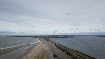 Aerial view drone shot of dam road N57 brouwersdam between north sea and Zeeland salt water lake Grevelingenmeer. Dutch industrial engineering frontier protecting country land from flooding - 775336375
