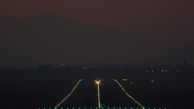 The airplane rises from the illuminated runway in the evening