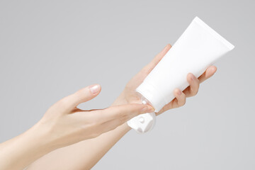 Female hands holding blank white plastic cosmetic tube on white background. Mockup