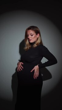 Pregnant woman in contemplation, hand on stomach. Child bearing concept