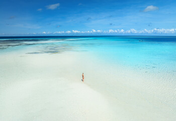 Aerial view of alone young woman on the sandbank in ocean, white sand, blue sea during low tide at sunny summer day in Nakupenda, Zanzibar island. Top view of girl, sand spit, water, sky with clouds - 775343155