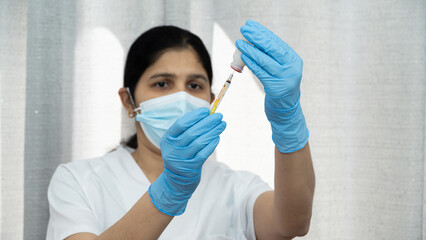 A woman in a white shirt and blue gloves is holding a syringe and giving a shot