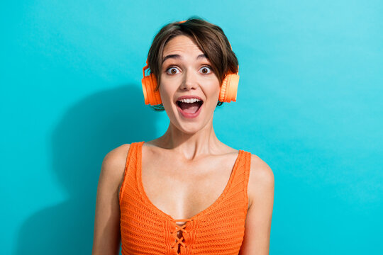 Photo of ecstatic nice woman dressed knitwear singlet listen music in headphones astonished staring isolated on turquoise color background