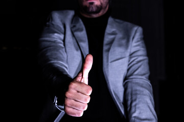 Businessman giving thumbs up in low light