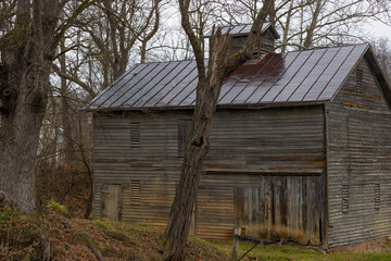 Barn sits amongest trees next to a road in rural Virginia, USA.