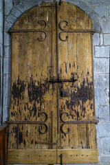 Porte en bois médiévale ancienne et rongée par le temps de l'église catholique d'Orcival dans les monts Dore en Auvergne