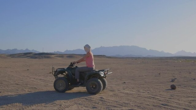 Quad bike ride through the desert near Hurghada, Egypt. Adventures in a desert. Sand, rocks and sunset. Woman is riding a quad bike. Happiness and joy. 