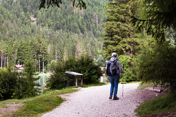 Fototapeta na wymiar A man walking on a mountain path with a backpack on his shoulders. Summer vacation, healthy lifestyle.