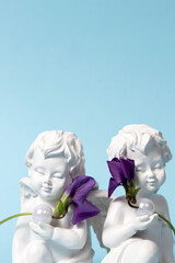 Angels holding white pearls and wild violet flowers on a blue background