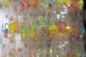 Sweet sugar pacifiers wrapped in transparent cellophane, bokeh Pic.
