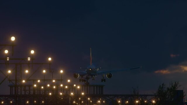 Airplane with landing gear out approaching a brightly lit runway at dusk