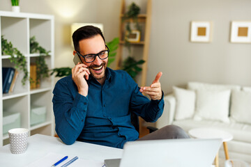 Young happy man talking on the phone in home office - 775374511