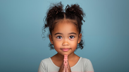 Portrait of a kid praying and looking at the camera