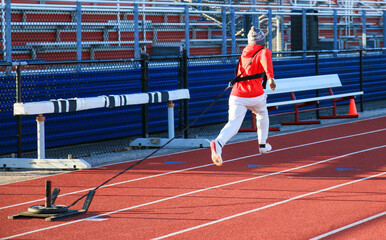 Male runner running while pulling a sled with weight on top on a track