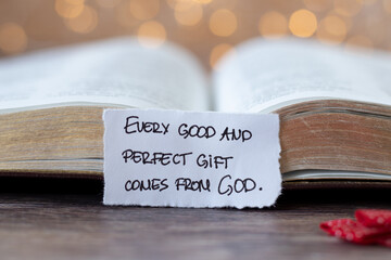 Every good and perfect gift comes from God, handwritten quote in front of open holy bible book with...