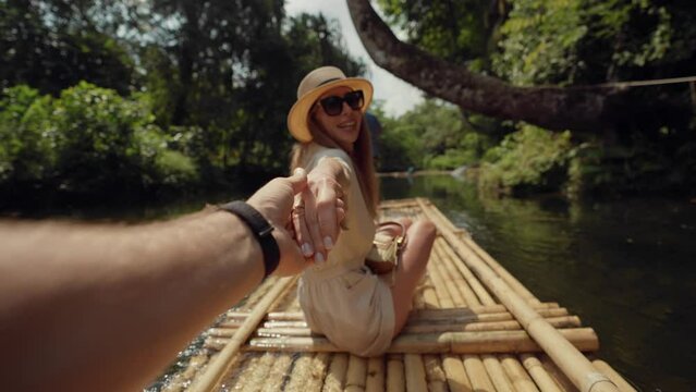 Female tourist floats on bamboo raft. Woman tourist enjoying the bamboo rafting on the river with man beautiful nature landscape on smartphone. Vacation, tropical tourism, travel, follow me concept.