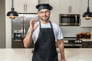 Chef cook with ok sign, delicious food. Portrait of chef man in a chef cap in the kitchen. Man...