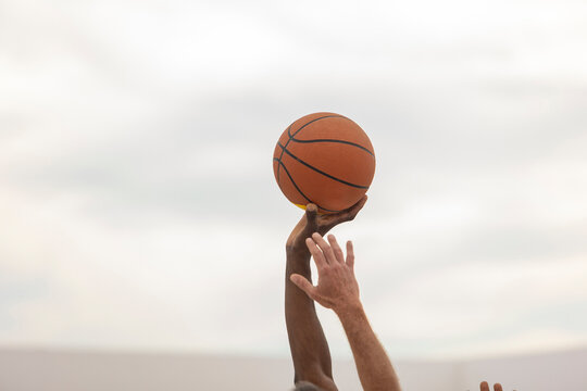 A basketball held steady in the hand of a player against a soft-focus background, ready for action on the outdoor court