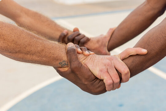 Close-up of multiethnic basketball players' hands gripping each other in a circle, displaying a powerful symbol of team commitment and trust