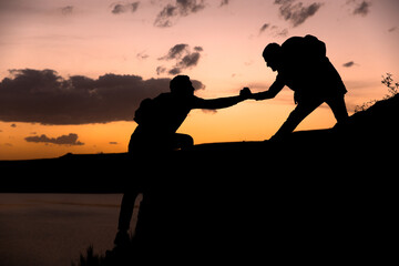 mountain climbers help each other to climb the mountain, sunset, helping a friend. stock photo