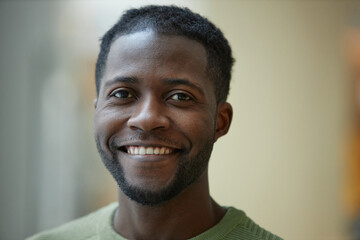 Closeup portrait of smiling Black man looking at camera with blurred background in green tones copy...