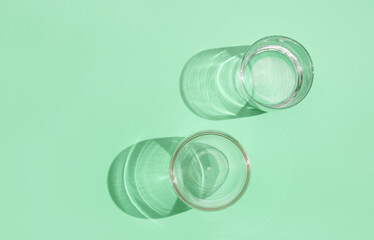 Empty glasses on green pastel background, top view