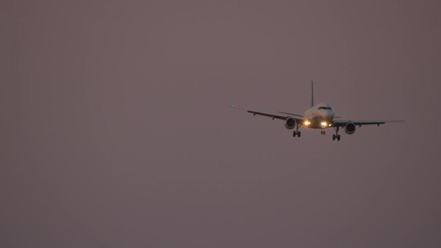 Front view of the aircraft with the landing lights on, during the last approach in the dim light of dusk