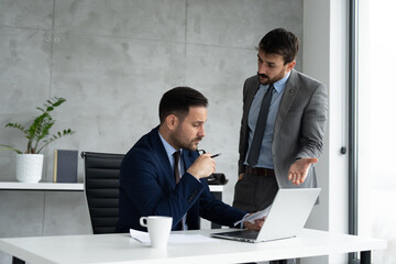 Two businessmen at office desk with laptop