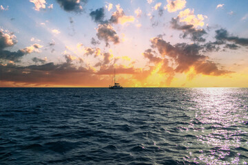 A boat sailing on the rippling blue waters of the Pacific Ocean off the coast of Oahu at sunset at...