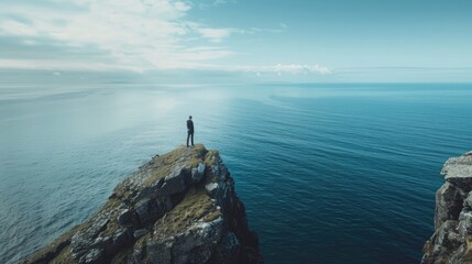 Individual on rocky promontory gazes over serene ocean, promoting World Oceans Day awareness, horizon stretching far and wide in the view - obrazy, fototapety, plakaty