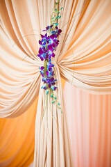Purple orchid arrangement on ivory drapes