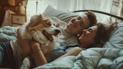 Young couple in love lying on the sofa in the bedroom with their beloved dog, having fun and enjoying each other on their weekend.  - obrazy, fototapety, plakaty