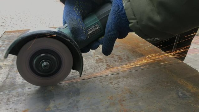 The process of electric cutting of metal structures. Bright flames and sparks. Master in work gloves.
