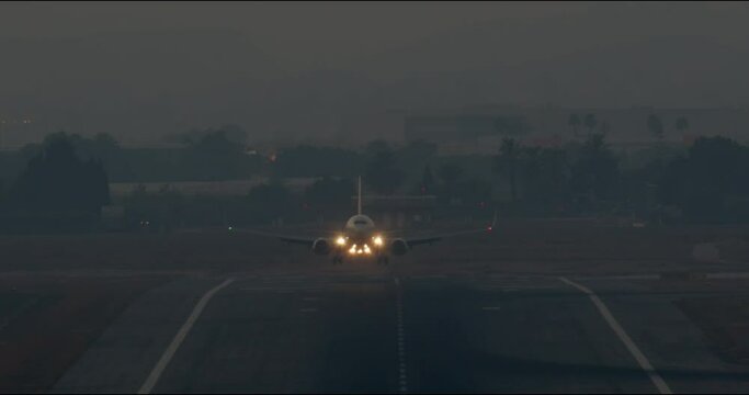 The plane landed on the runway with the landing lights on at dusk - slow motion