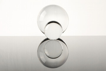 Transparent glass balls on mirror surface against light background
