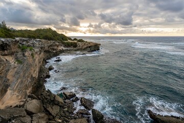 The sun slowly rises over jagged cliffs, which meet the rough turquoise waters of the Pacific Ocean...